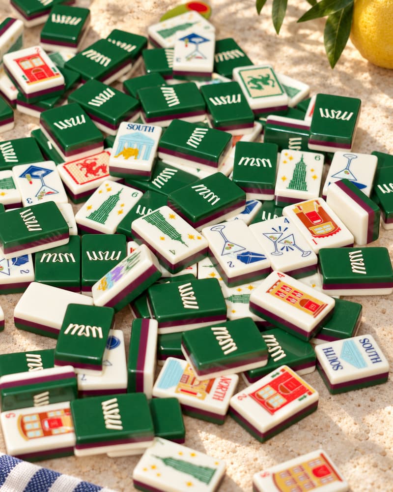 Manhattan Set tiles scattered on a sunny stone table, with deep green backs and city faces
